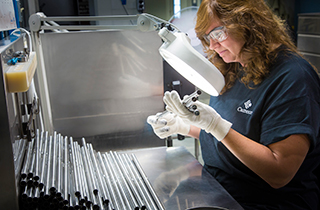 Female Cameco employee looking at rods under a magnifying glass light